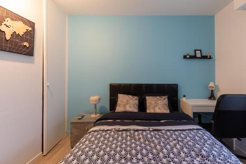 a bedroom with a bed with a blue wall at Le Beau Refuge Parisien de Cergy - Parisian modern flat at Cergy in Cergy
