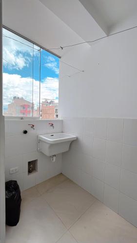 baño blanco con lavabo y ventana en Duplex Horacio Zeballos, en Cajamarca