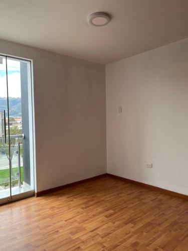 Habitación vacía con ventana grande y suelo de madera. en Duplex Horacio Zeballos, en Cajamarca
