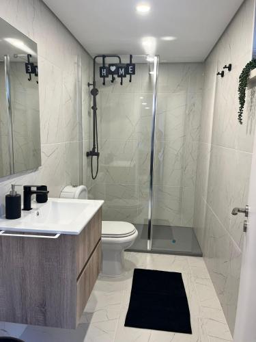 a bathroom with a shower and a toilet and a sink at Casinha Rés do Chão na Nazaré com Quintal e Barbecue in Nazaré