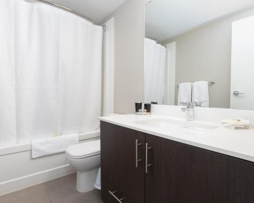 a white bathroom with a sink and a toilet at Hendrix Luxury Apartments by Corporate Stays in Edmonton