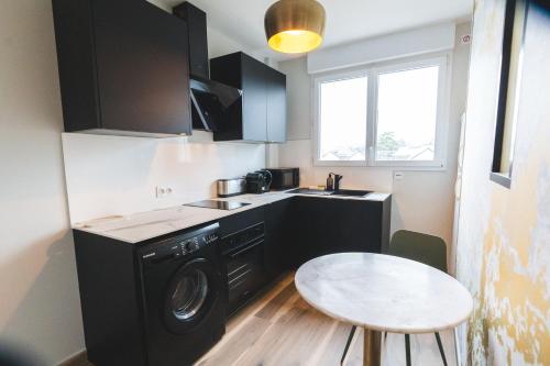 a small kitchen with a washing machine and a table at LE GOLDEN Gare SNCF - Résidence calme in Laval