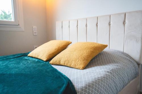 Una cama con dos almohadas amarillas encima. en LE GOLDEN Gare SNCF - Résidence calme, en Laval