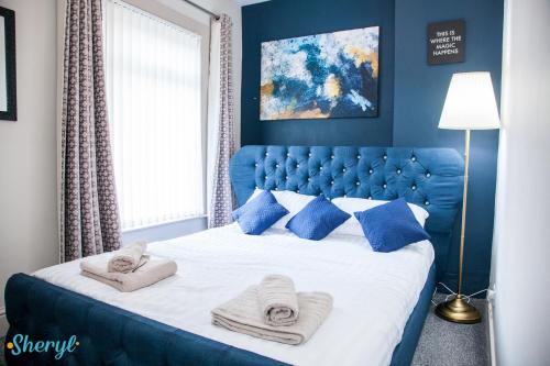 a blue bedroom with a large bed with towels on it at Liverpool City Grandeur by Sheryl - Close to City Center, Anfield Stadium and Airport with free business super fast fibre broadband in Liverpool