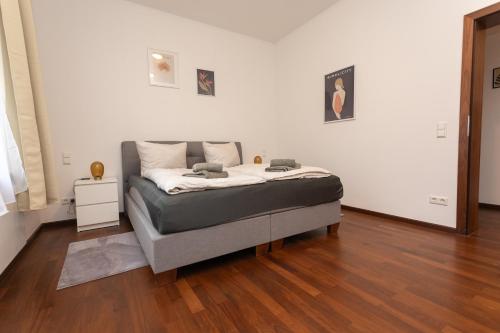 a bed in a white room with a wooden floor at Stadthaus mit 2 Schlafzimmern & Wohnzimmer mit Kamin - Kostenloser Privat-Parkplatz auf dem Grundstück in Leipzig