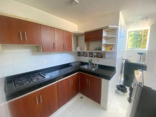 cocina con armarios de madera, fregadero y nevera en Apartamento entero amoblado 201, en Barranquilla