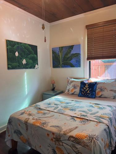 a bedroom with a bed and two paintings on the wall at The Cottage at Pineapple House in West Palm Beach