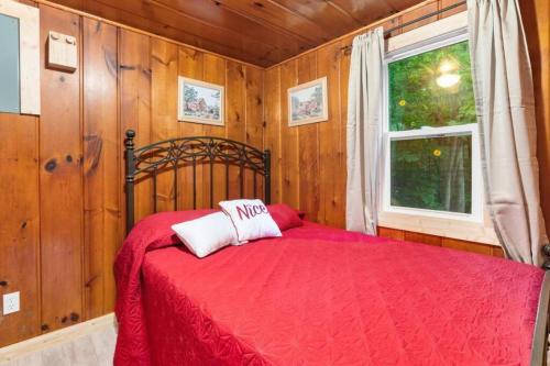 a bedroom with a red bed and a window at Paradise Lake Hidden Gem in Carp Lake