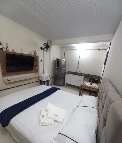 a bedroom with a bed and a tv and a kitchen at Condomínio Village Paraty in Paraty