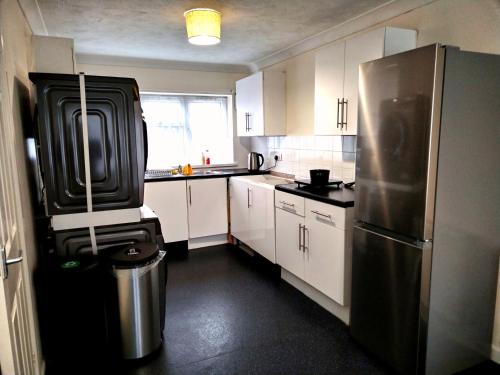 uma cozinha com um frigorífico de aço inoxidável e armários brancos em Comfort Private Rooms in Three bedroom House em Bridgemary
