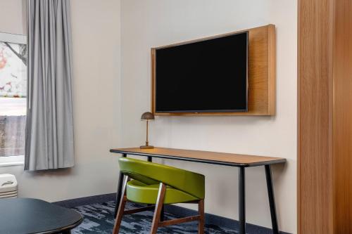 a room with a desk and a television on a wall at Fairfield by Marriott Inn & Suites Harrisburg West/Mechanicsburg in Mechanicsburg