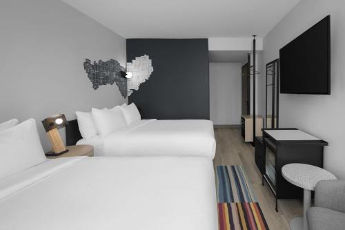 a hotel room with two beds and a flat screen tv at Aloft New York Chelsea in New York