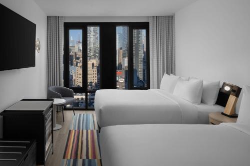 a hotel room with two beds and a large window at Aloft New York Chelsea in New York