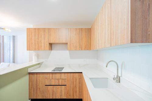 una cocina con armarios de madera y fregadero en Casa Ambar Apartments, en Panamá