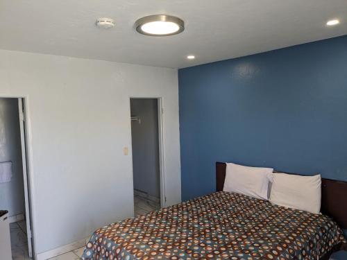 a room with a bed with a blue wall at Green spot motel in Victorville