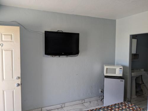 a flat screen tv hanging on a wall next to a microwave at Green spot motel in Victorville