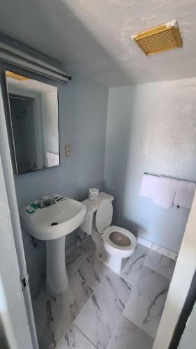 a white bathroom with a toilet and a sink at Green spot motel in Victorville