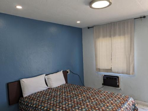 a bedroom with a bed with a blue wall at Green spot motel in Victorville