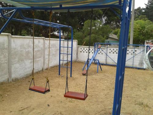 an empty playground with swings in the dirt at Cabaña Las Cruces, a pasos de la playa in Las Cruces