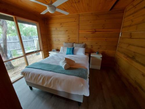 um quarto com uma cama num chalé de madeira em Bushland Cabin near Town, River and Restaurants em Echuca