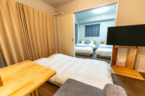 a hotel room with two beds and a flat screen tv at Sun Route Hirano-cho, サンルート平之町 in Kagoshima