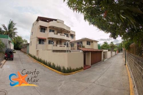 a large white building on the side of a street at Canto del Mar Hotel - Zihuatanejo - Suites con Cocina in Zihuatanejo
