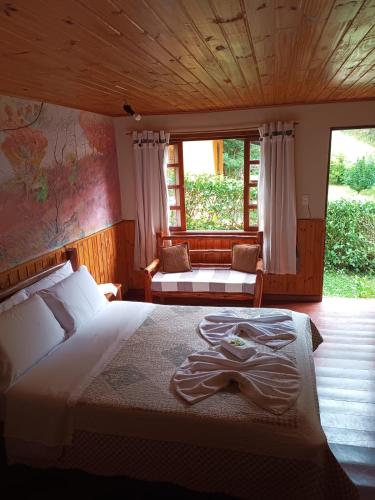 a bedroom with a bed and a couch and windows at Pousada da Carmem in Visconde De Maua