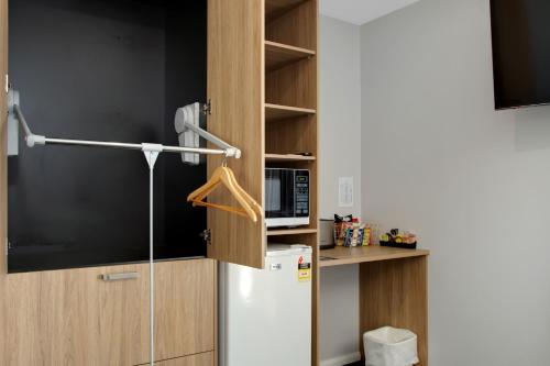 a small kitchen with a refrigerator and a microwave at Hive Hotel, Moruya in Moruya
