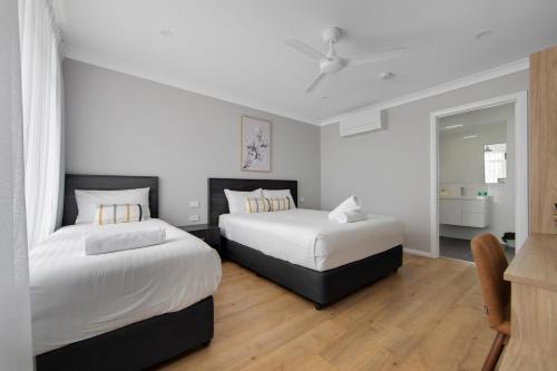 two beds in a room with white walls and wooden floors at Hive Hotel, Moruya in Moruya