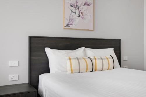 a bedroom with a white bed with a wooden headboard at Hive Hotel, Moruya in Moruya