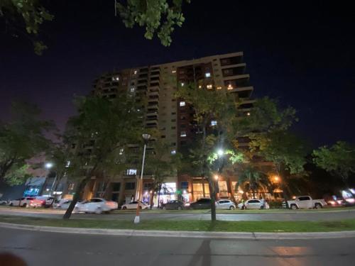 a tall building at night with cars parked in a parking lot at Hermoso departamento en avenida las heras, Resistencia Chaco in Resistencia