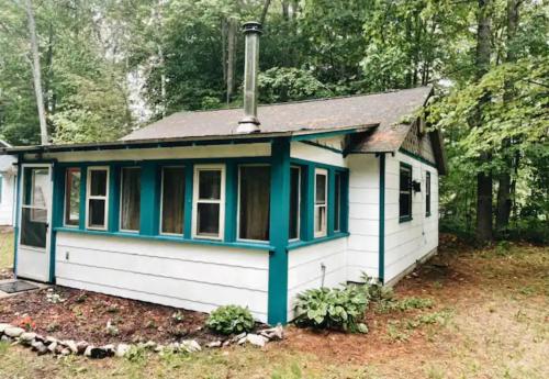 a small white and blue house in a yard at Up North No Worries - Close to Mackinac Island Ferry! in Carp Lake