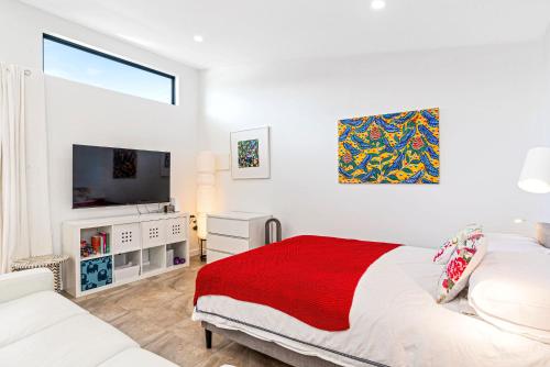 een witte slaapkamer met een bed en een televisie bij Eco Bee Studio in Garden Serenity in Thebarton