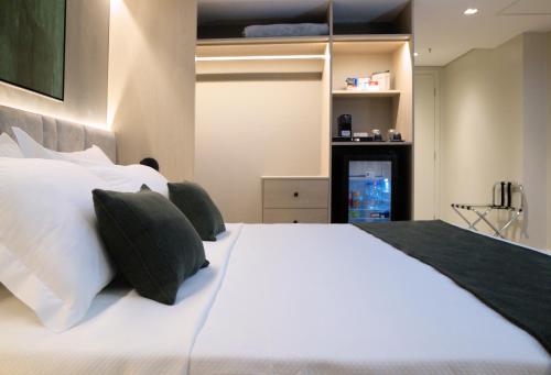 ein Schlafzimmer mit einem großen weißen Bett mit grünen Kissen in der Unterkunft HIGI HOTEL SÃO PAULO in São Paulo