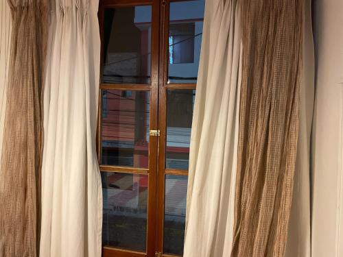 a wooden window with white curtains in a room at SierraAlta in Chivay