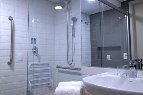 uma casa de banho com um lavatório e uma cabina de duche em vidro. em HIGI HOTEL SÃO PAULO em São Paulo