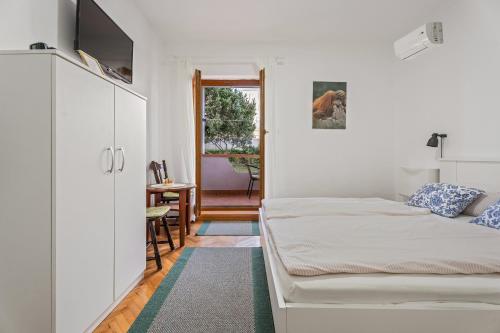 sypialnia z 2 łóżkami, stołem i oknem w obiekcie Apartments and rooms by the sea Grebastica, Sibenik - 13942 w mieście Grebaštica