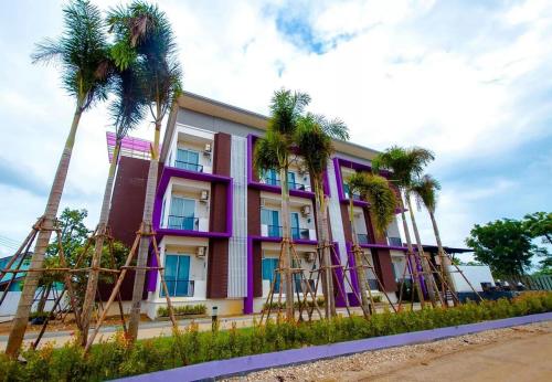 a purple building with palm trees in front of it at FIG Boutique Hotel in Kamphaeng Phet