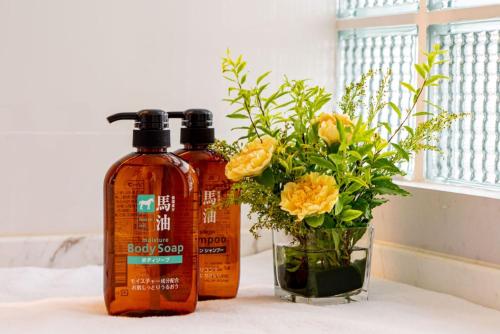 two bottles of shampoo and a vase with flowers at Wuyu Hotel - Chongqing Jiangbei Airport & Light Rail in Chongqing