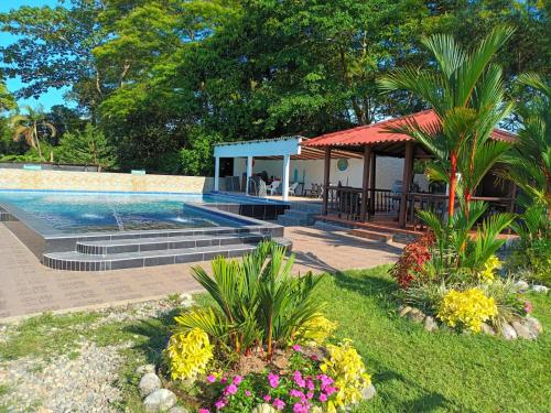 a swimming pool with a gazebo and flowers at HOSPEDAJE VILLA CAMPESTRE "ALONDRA" Parqueo Privado GRATIS! in Villavicencio