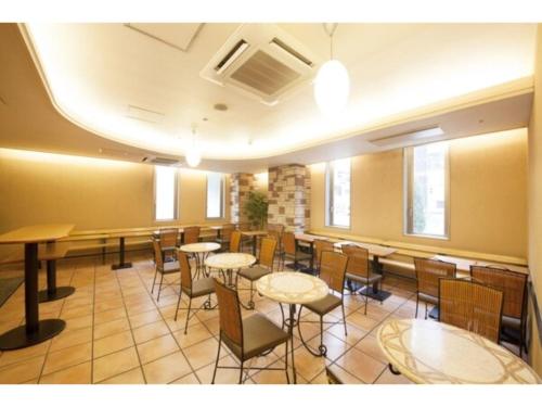 uma sala de jantar com mesas, cadeiras e janelas em R&B Hotel Sapporo Kita 3 Nishi 2 - Vacation STAY 39507v em Sapporo