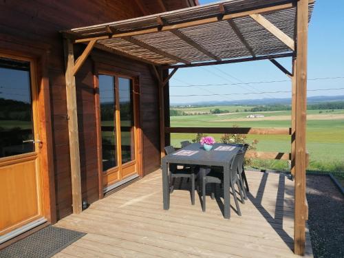 une terrasse en bois avec une table et des chaises. dans l'établissement Chalet cosy avec jardin, parking et recharge VE aux portes des Vosges - FR-1-584-16, à Barbas