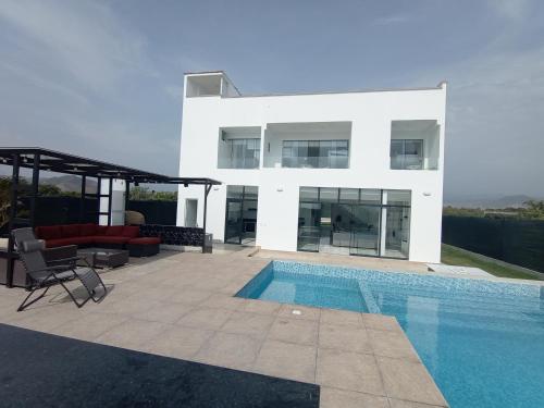 a white house with a swimming pool in front of it at Alquilo Casa playa in San Antonio
