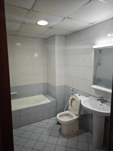 a bathroom with a toilet and a sink and a tub at Sea View Studio in Ajman