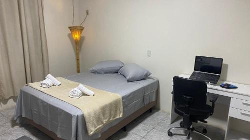 1 dormitorio con 1 cama y escritorio con ordenador portátil en Conforto e tranquilidade no centro, en Foz do Iguaçu