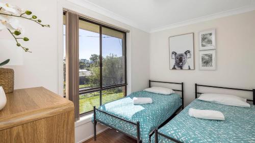 two twin beds in a room with a window at Walking Distance to Shoal Bay Beach in Shoal Bay
