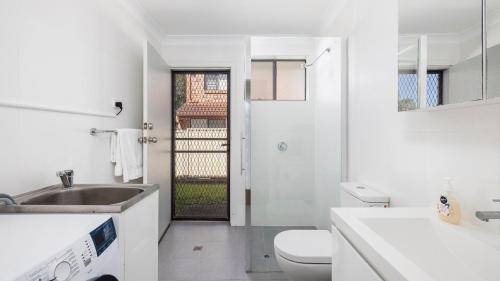 a white bathroom with a sink and a toilet at Walking Distance to Shoal Bay Beach in Shoal Bay
