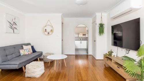a living room with a couch and a tv at Walking Distance to Shoal Bay Beach in Shoal Bay