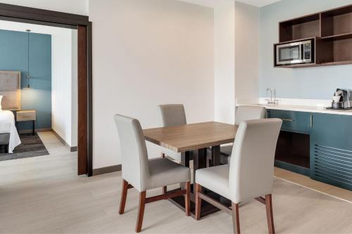 a kitchen and dining room with a wooden table and chairs at Courtyard by Marriott San Jose Airport Alajuela in Alajuela City