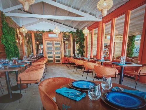 a restaurant with tables and chairs with blue plates on them at MANBANA 320 RESIDENCE KAWANN in Grand-Bourg